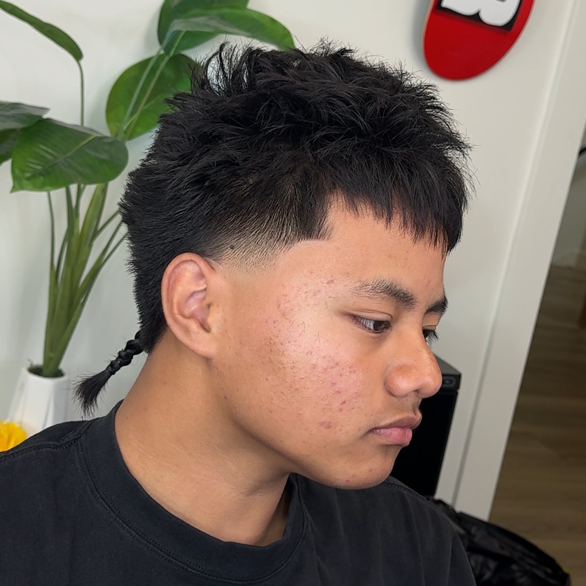 Textured mullet haircut with braided tail and low fade